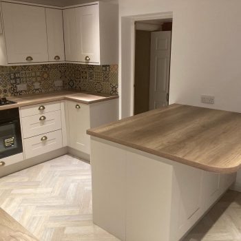close up image of white kitchen with wood worktop